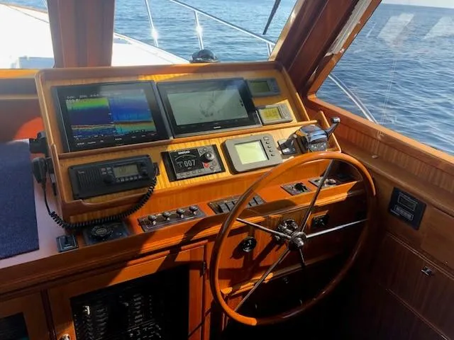 Slide: The Image of 2003 Lyman-Morse Wesmac Sportfish Cruiser helm with navigation screens and wooden steering wheel. - 3