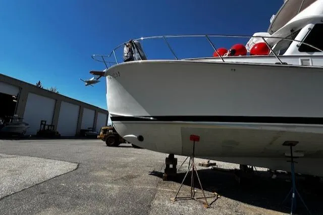 Slide: The Image of 2003 Lyman-Morse Wesmac Sportfish Cruiser on stands in a boatyard under clear blue sky. - 30