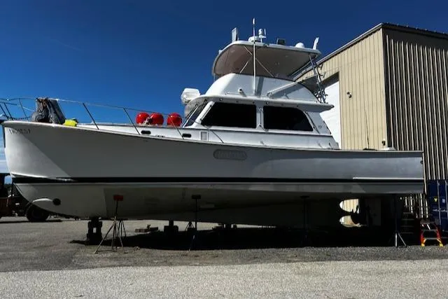 Slide: The Image of 2003 Lyman-Morse Wesmac Sportfish Cruiser on dry dock, white hull, near a building. - 39