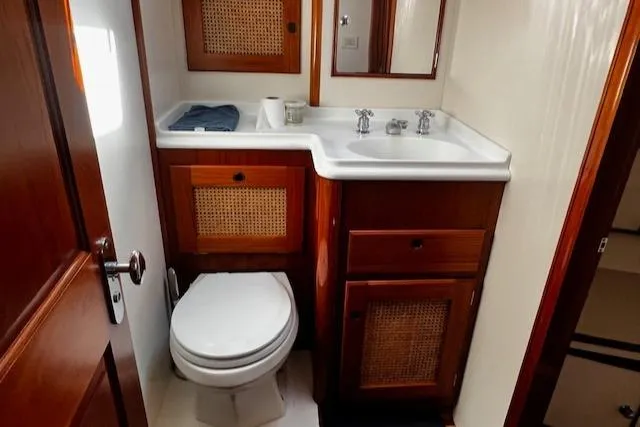 Slide: The Image of Bathroom interior of 2003 Lyman-Morse Wesmac Sportfish Cruiser with wooden cabinetry and white fixtures. - 44