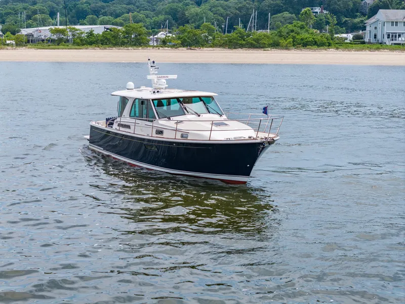 Slide: The Image of 2024 Sabre 43 Salon Express yacht cruising on calm waters near a sandy shoreline. - 11