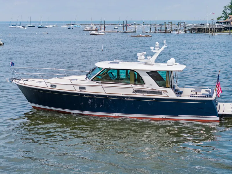 Slide: The Image of 2024 Sabre 43 Salon Express yacht on calm waters, docked with scenic marina background. - 12