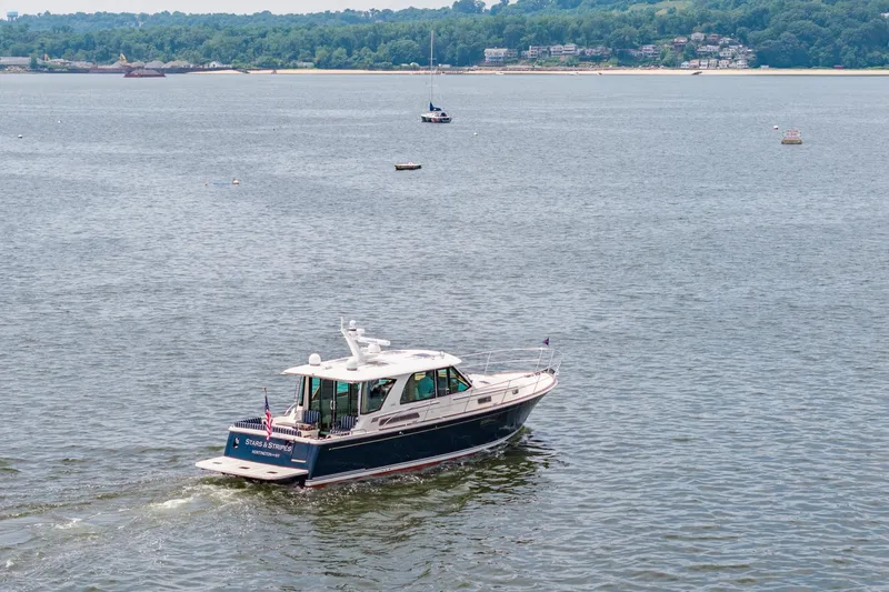 Slide: The Image of 2024 Sabre 43 Salon Express cruising on a scenic lake with distant shoreline. - 15