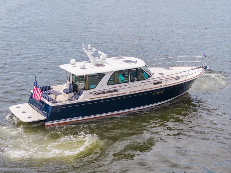 Slide: The Image of 2024 Sabre 43 Salon Express yacht cruising on open water, displaying American flag. - 2