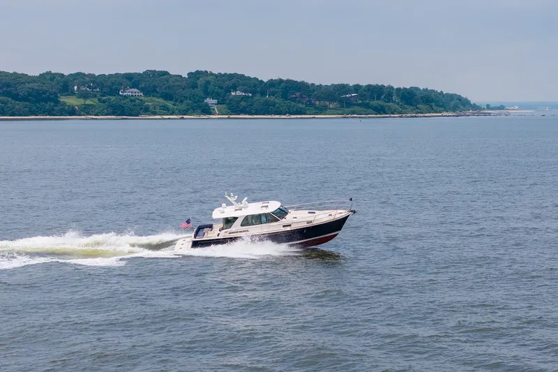 Slide: The Image of 2024 Sabre 43 Salon Express cruising on open water near a lush coastline. - 22