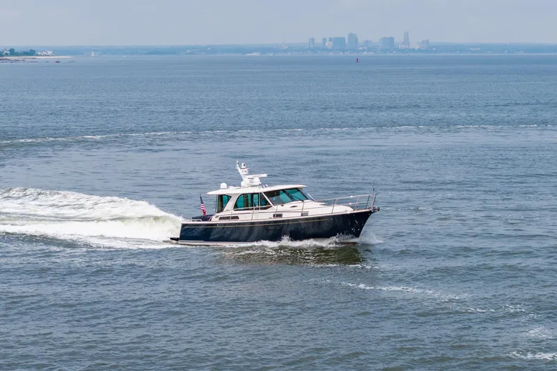 Slide: The Image of 2024 Sabre 43 Salon Express cruising on open water with city skyline in background. - 23