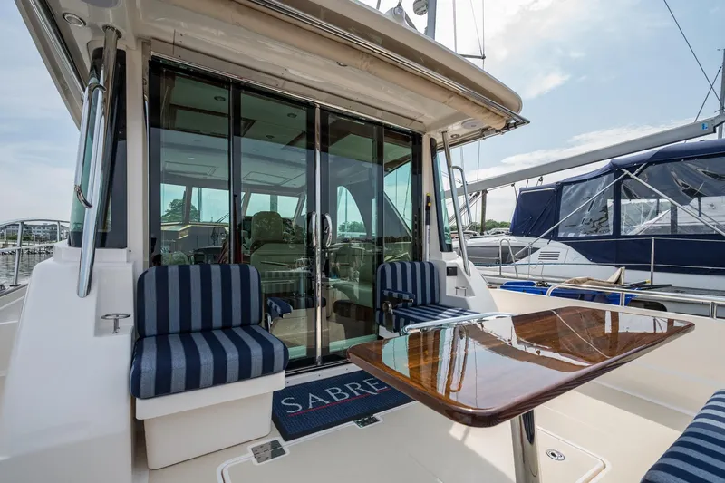 Slide: The Image of 2024 Sabre 43 Salon Express yacht with striped seating and polished wood table. - 28