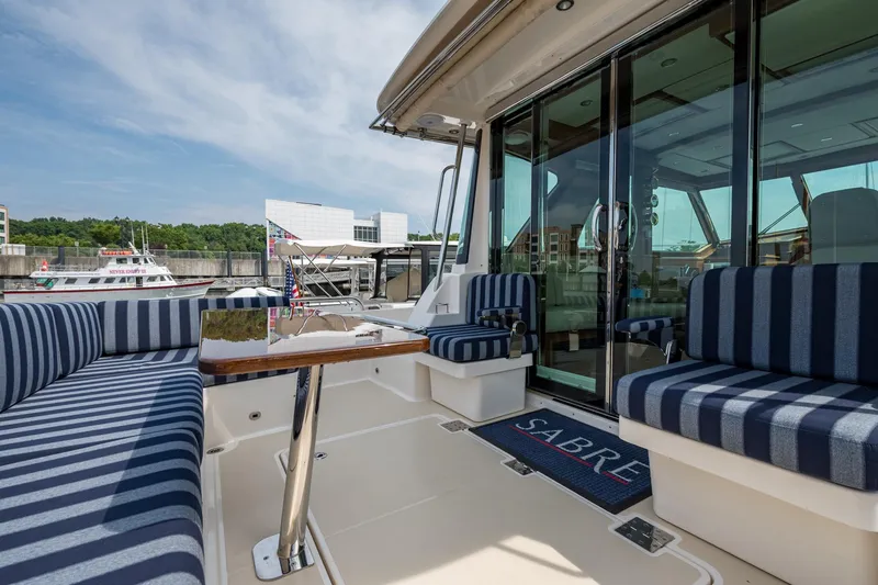 Slide: The Image of 2024 Sabre 43 Salon Express yacht with striped seating and glass doors at a marina. - 29