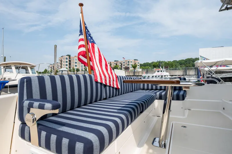 Slide: The Image of 2024 Sabre 43 Salon Express yacht with striped seating and American flag at marina. - 30