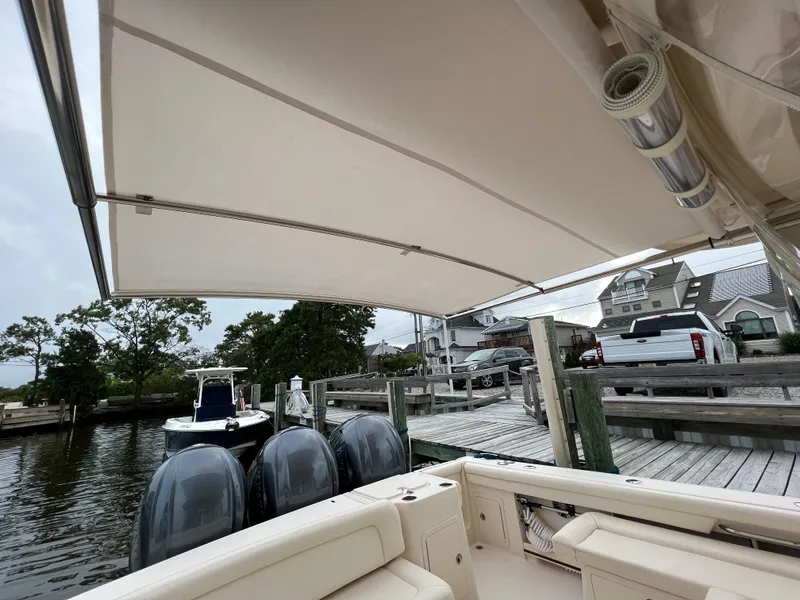 Slide: The Image of 2020 Grady-White Freedom 375 boat docked, featuring triple outboard engines and a spacious canopy. - 23