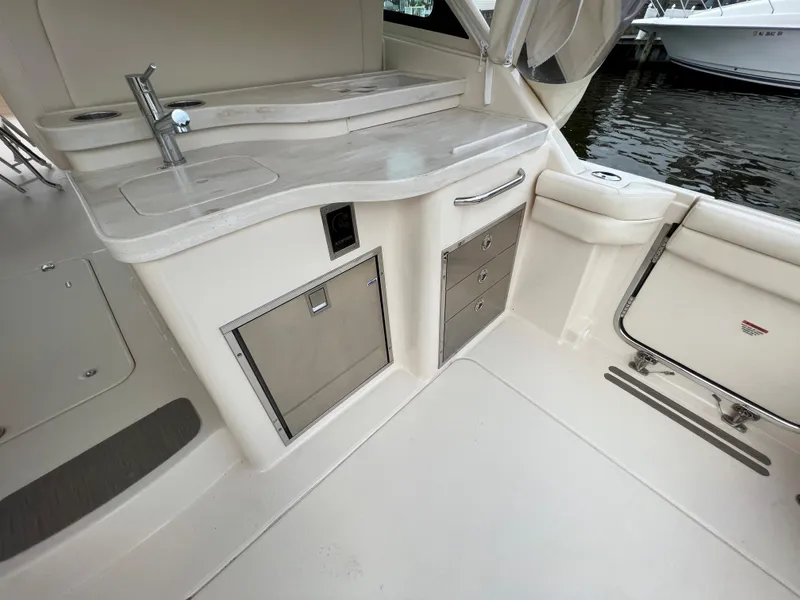 Slide: The Image of 2020 Grady-White Freedom 375 boat interior with kitchenette and storage, docked by the water. - 47