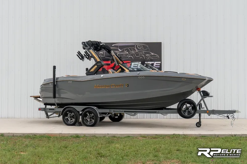 The Image of 2025 MasterCraft X22 boat on trailer, gray exterior, displayed outdoors. - 0