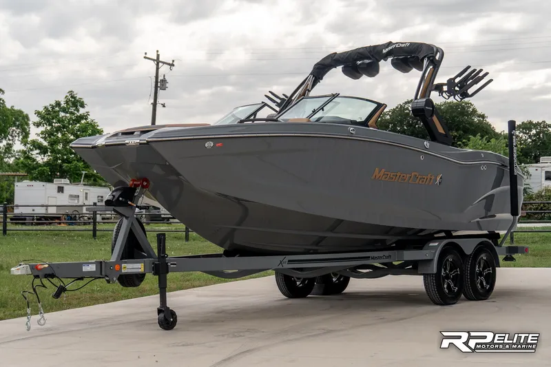 Slide: The Image of 2025 MasterCraft X22 boat on trailer, sleek gray design, parked outdoors. - 10