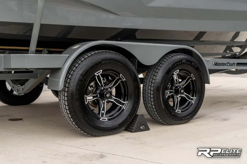 Slide: The Image of 2025 MasterCraft X22 trailer with black alloy wheels and dual axles. - 16