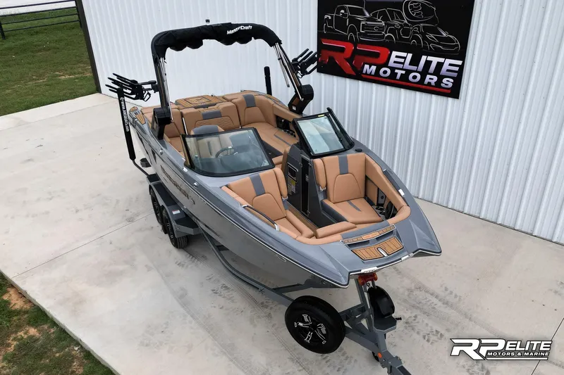 Slide: The Image of 2025 MasterCraft X22 boat with tan interior at RP Elite Motors showroom. - 2