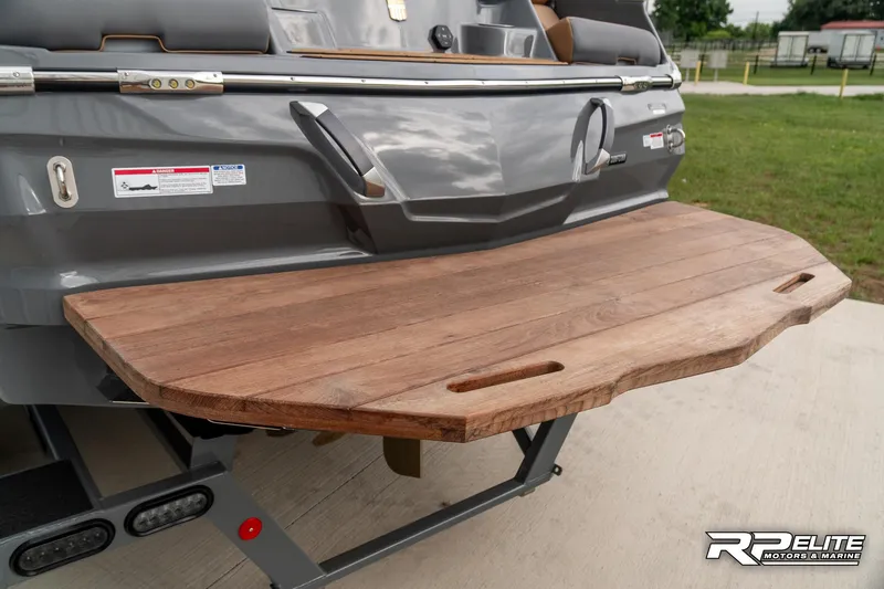 Slide: The Image of 2025 MasterCraft X22 boat with wooden swim platform, parked outdoors. - 33