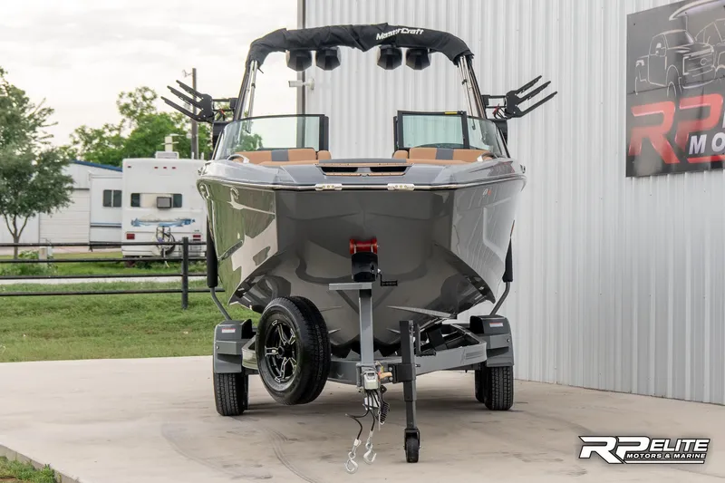 Slide: The Image of 2025 MasterCraft X22 boat on trailer, parked outdoors near a building. - 8