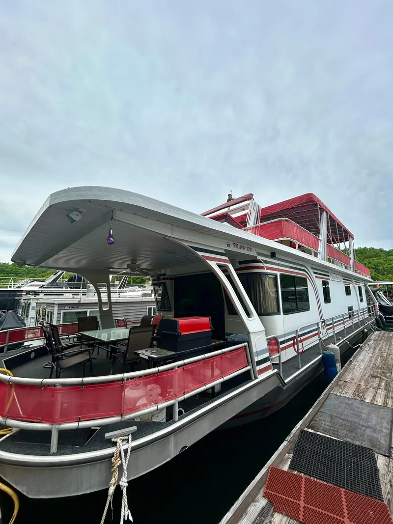 Slide: The Image of 2001 Jamestowner houseboat with red accents docked at a marina. - 1
