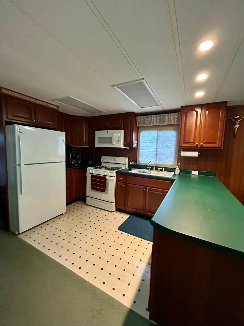 Slide: The Image of 2001 Jamestowner houseboat kitchen with green countertops, white appliances, and wood cabinetry. - 10