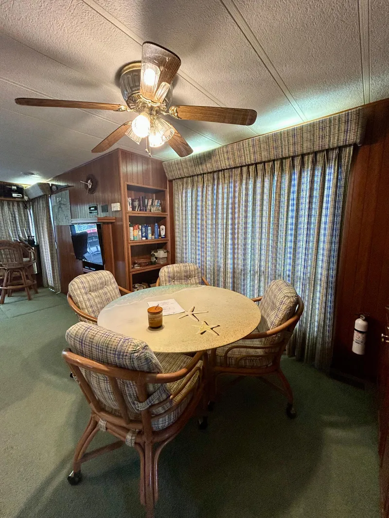 Slide: The Image of 2001 Jamestowner houseboat interior with dining area, ceiling fan, and cozy seating. - 11