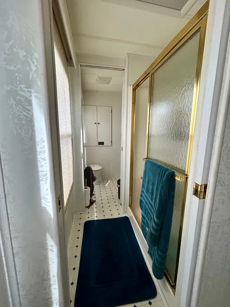 Slide: The Image of 2001 Jamestowner houseboat bathroom with gold-framed shower, blue towels, and patterned flooring. - 16