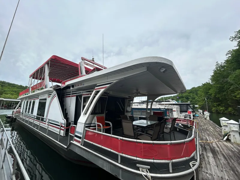 Slide: The Image of 2001 Jamestowner houseboat docked, featuring red and white exterior with upper deck seating. - 2