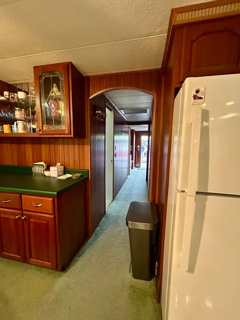 Slide: The Image of Interior of a 2001 Jamestowner houseboat with wooden cabinets and a white refrigerator. - 21