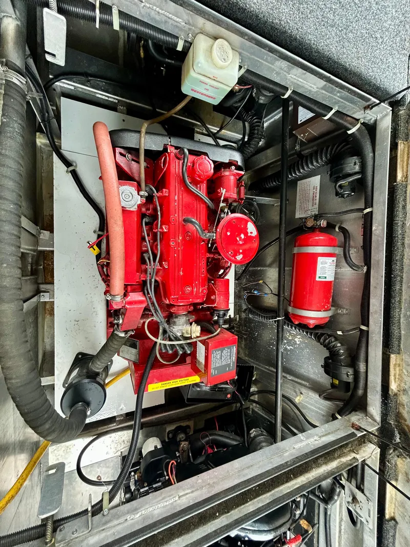 Slide: The Image of Engine compartment of a 2001 Jamestowner houseboat, featuring a red engine and fire extinguisher. - 29