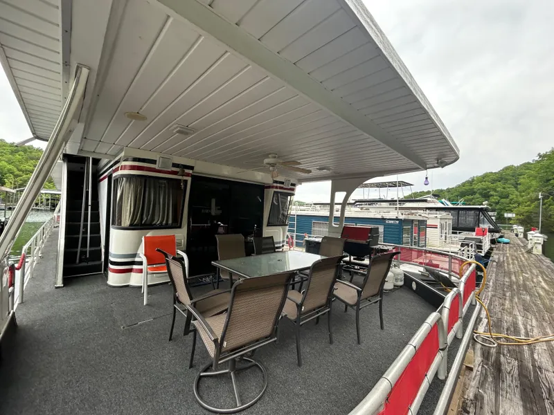Slide: The Image of 2001 Jamestowner houseboat with outdoor seating on a dock, surrounded by lush greenery. - 3