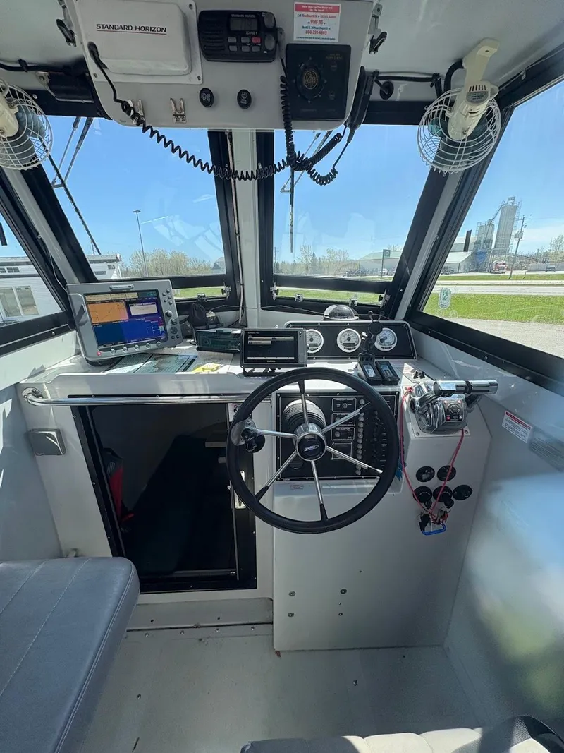 Slide: The Image of 2002 Boston Whaler 27 Vigilant cockpit with steering wheel, controls, and navigation equipment. - 11