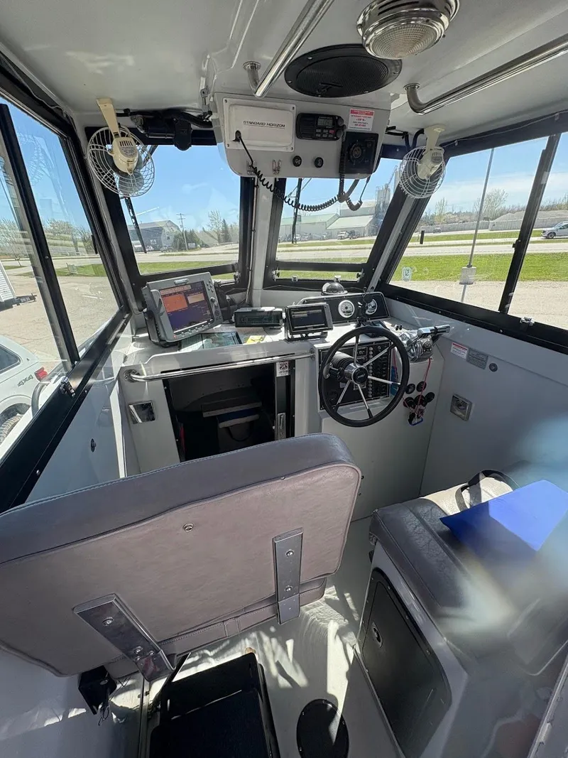 Slide: The Image of Interior of a 2002 Boston Whaler 27 Vigilant boat, featuring steering wheel and navigation equipment. - 12