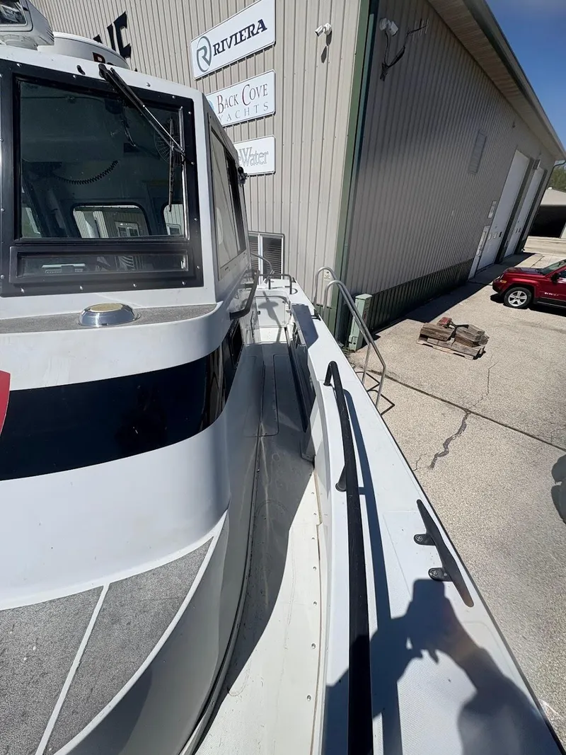 Slide: The Image of 2002 Boston Whaler 27 Vigilant boat docked near a building under clear skies. - 6