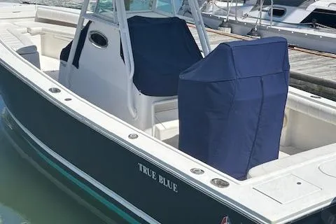 Slide: The Image of 2013 Regulator 26 FS boat named "True Blue" docked with covered seats. - 10