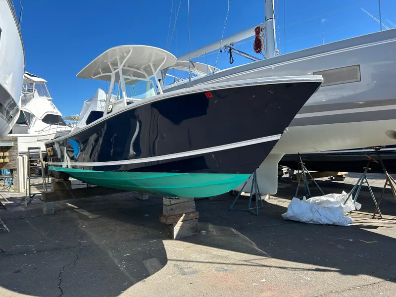Slide: The Image of 2013 Regulator 26 FS boat on dry dock, blue hull, white top, sunny day. - 2
