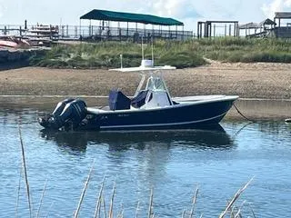 Slide: The Image of 2013 Regulator 26 FS boat anchored in calm waters near a sandy shore. - 3