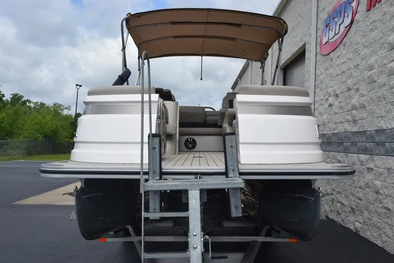 Slide: The Image of 2022 Silver Wave 2410 SW5 JS pontoon boat on trailer, parked near building. - 3