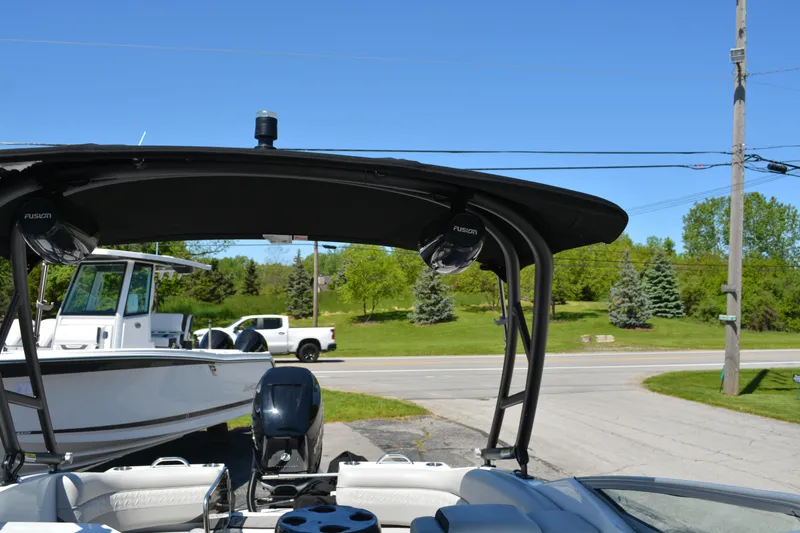 Slide: The Image of 2022 Hurricane SunDeck 2690 OB boat with canopy and speakers, parked near a road. - 10