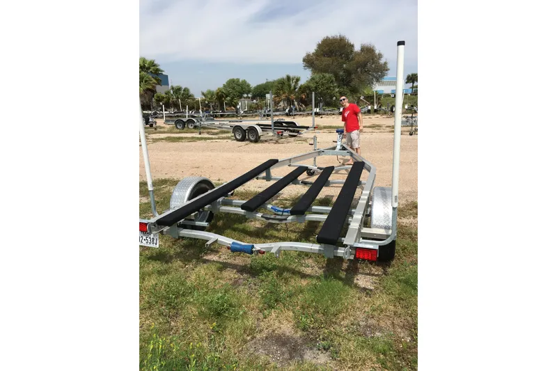 Slide: The Image of 2016 Mako 18 LTS boat trailer on grassy lot with person in background. - 12