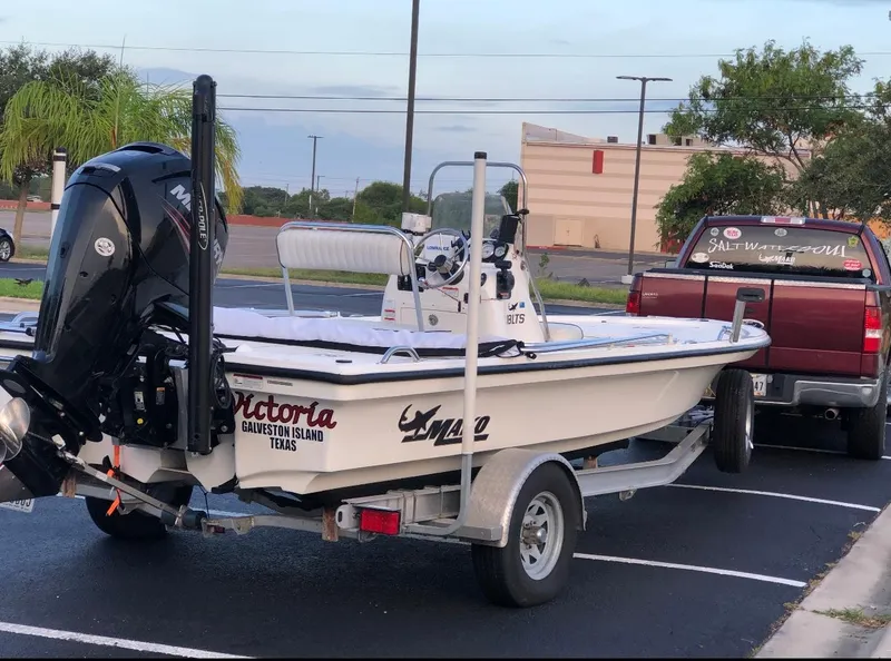 Slide: The Image of 2016 Mako 18 LTS boat on trailer with Mercury engine, parked outdoors. - 2