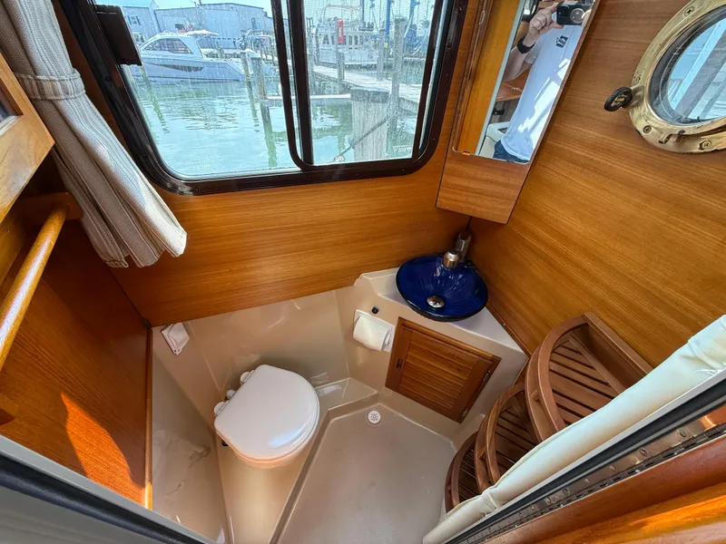 Slide: The Image of 2017 Ranger Tugs R-27 boat bathroom with wooden interior, toilet, and sink. - 12