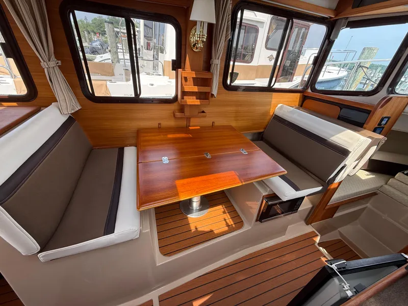 Slide: The Image of Interior of 2017 Ranger Tugs R-27 with wood table and seating area. - 14
