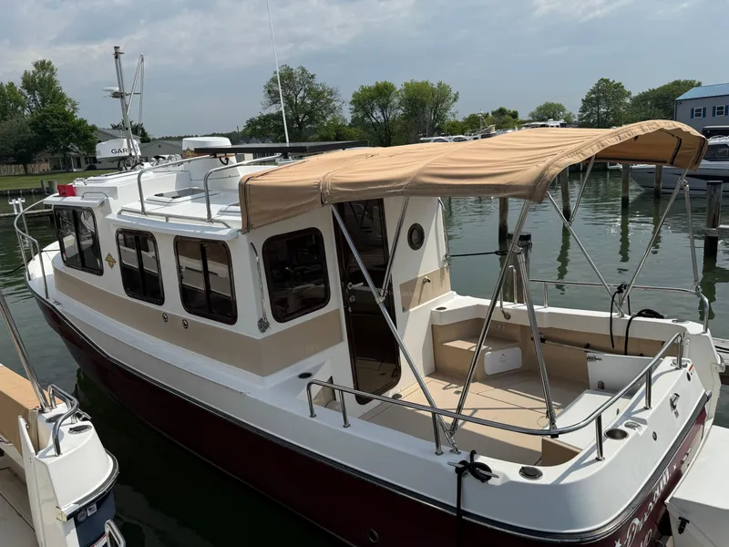 Slide: The Image of 2017 Ranger Tugs R-27 boat docked, featuring a beige canopy and spacious deck. - 4
