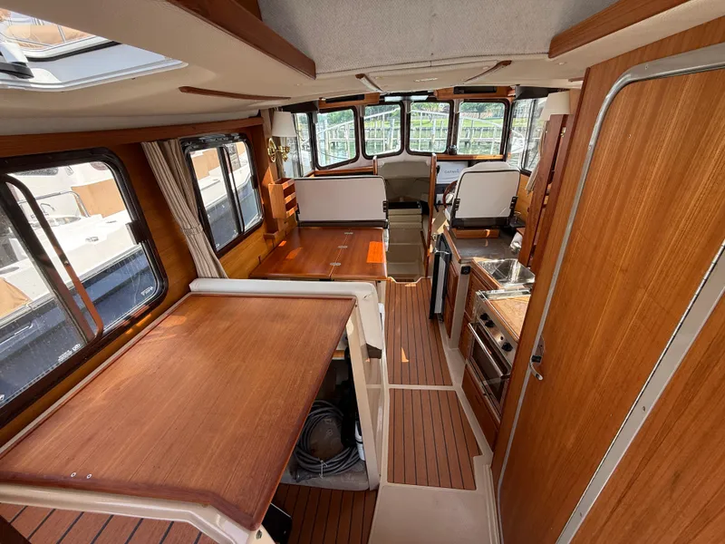 Slide: The Image of 2017 Ranger Tugs R-27 interior with wood finish, kitchen, and seating area. - 7