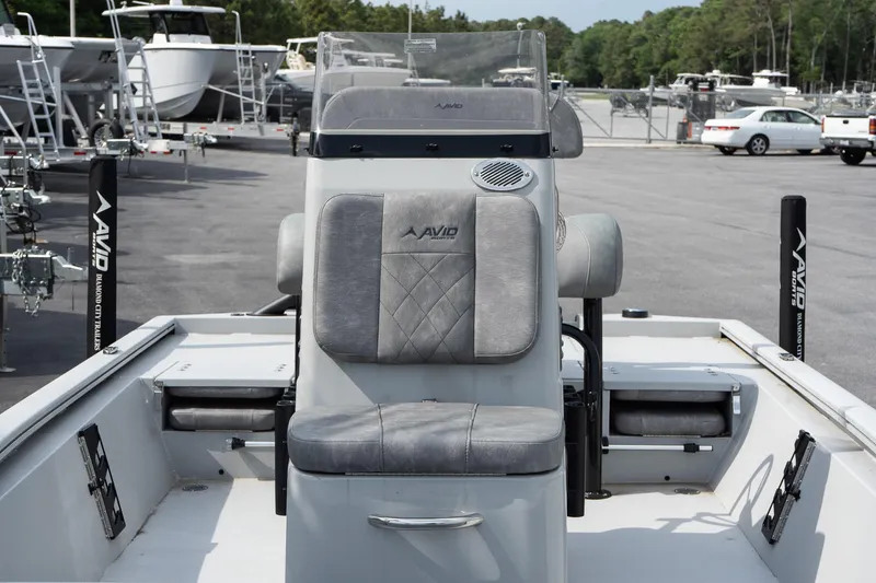 Slide: The Image of 2025 Avid 19 FSX boat interior with gray seating and console, parked in a marina. - 12