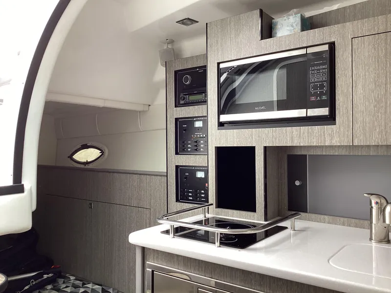 Slide: The Image of 2022 Monterey 295 Sport Yacht interior with modern kitchenette, featuring microwave and sleek cabinetry. - 17