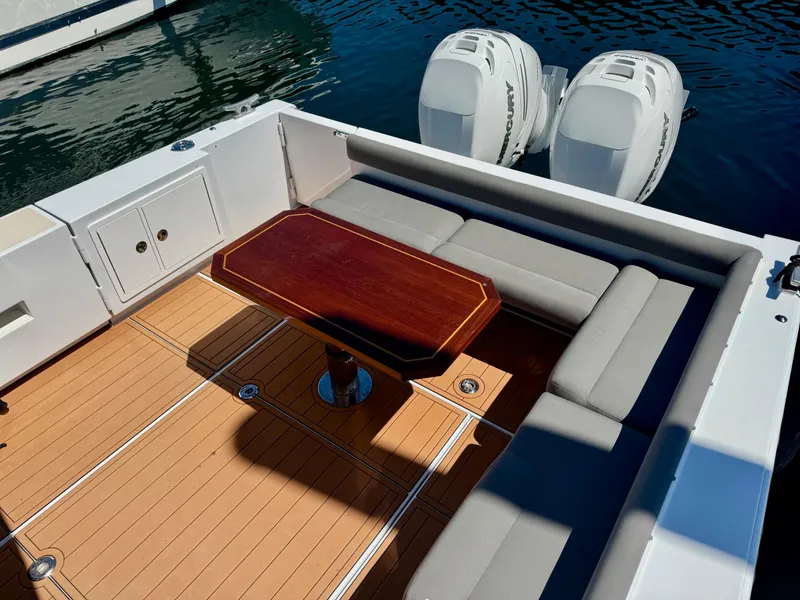 Slide: The Image of 2020 Coastal Craft 33 Express boat with teak deck, cushioned seating, and dual outboard engines. - 7