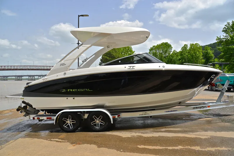 Slide: The Image of 2022 Regal LS4 boat on trailer, sleek black and white design, parked near water. - 18