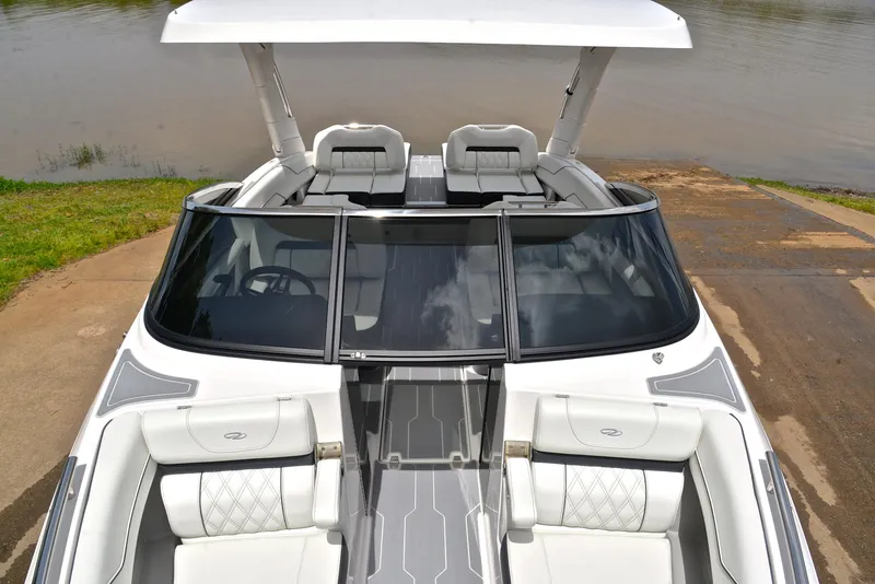 Slide: The Image of 2022 Regal LS4 boat with sleek design, white seating, and modern dashboard by the water. - 24