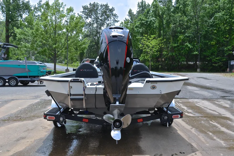 Slide: The Image of 2020 Vexus AVX1880 boat on trailer, rear view, parked on wet pavement, surrounded by trees. - 13