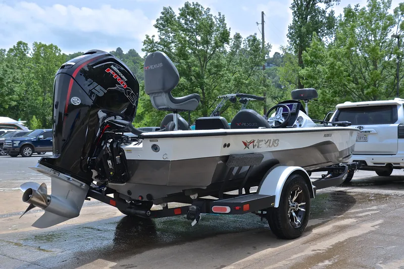 Slide: The Image of 2020 Vexus AVX1880 boat on trailer, parked outdoors with trees in background. - 14